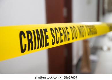 Crime Scene Tape In Front Of Room Door With Blurred Background