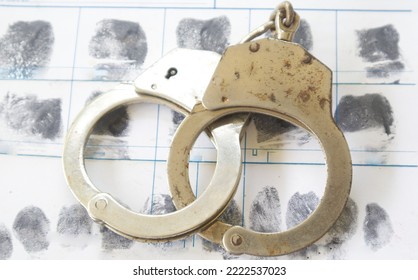 Crime and violence concept.Gun and Police Handcuffs on fingerprints crime page file
				