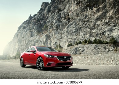 Crimea, Russia - September 20, 2015: Red car Mazda standing on the road near mountains at daytime