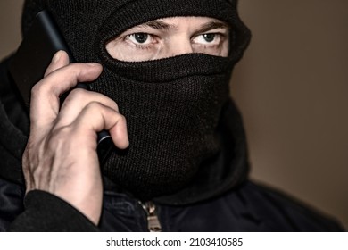 A Criminal In A Black Balaclava And A Hoodie In The Dark. The Concept Of Crime Growth, Robbery And Fraud, Unemployment And Malice.