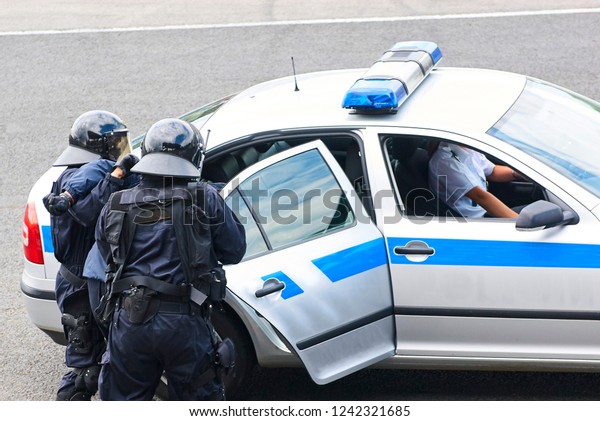 Criminal handcuffed and being shoved in the back of\
a squad car by a police officer. police arresting a criminal and\
taking him away in a police car. Intervention of a special police\
unit