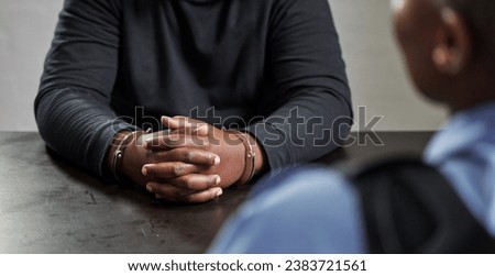 Criminal, hands and handcuffs and table for interrogation, questions or accusation with officer in room. Police talking to prisoner, gangster or thief for security, discussion or arrest in prison