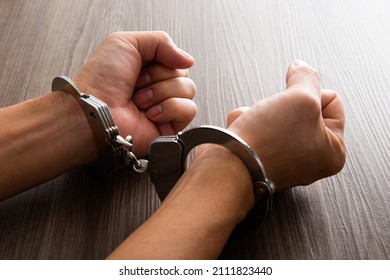 Criminal hands locked in handcuffs.