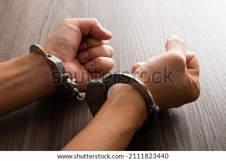 Criminal hands locked in handcuffs.
