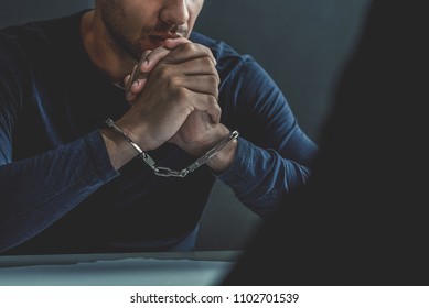 Criminal man with handcuffs in interrogation room being interviewed after committed a crime - Shutterstock ID 1102701539
