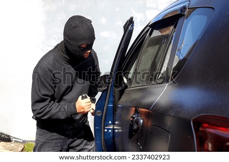 A criminal man with open the door and break into the car. He uses a screwdriver. Hijacker, the concept of car theft