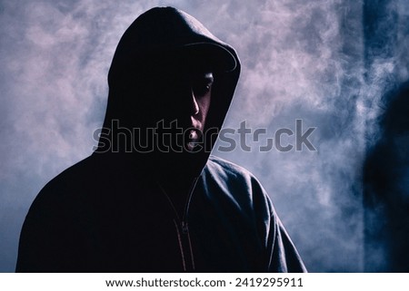 Criminal man in shadow. Scary suspicious stranger with hidden face. Silhouette of gangster with dark smoke fog background. Gang crime or horror concept. Hooligan, thief, hacker or pyromaniac.