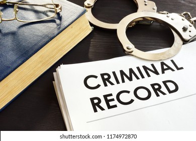 Criminal record and handcuffs on a desk.