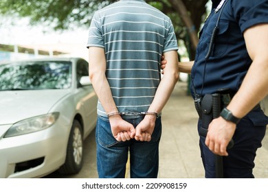Criminal suspect seen from behind with handcuffs getting arrested by the police because of drunk driving or car crash