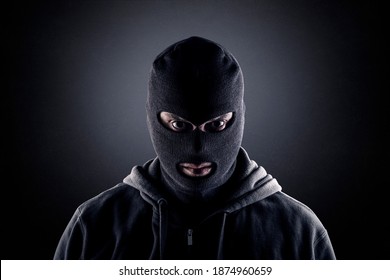 Criminal usando pasamontañas negras y capucha en la oscuridad