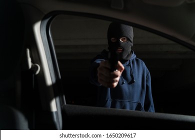 Criminal Wearing Ski Mask And Pointing Gun While Making Eye Contact In Parking Lot