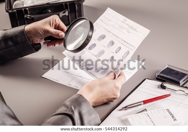 Criminology expert through a magnifying glass\
looking at a\
fingerprint