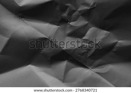 Crinkled paper background in grayscale, featuring a textured, abstract pattern with shadows and folds.