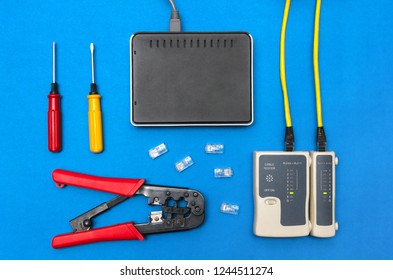 Cripmer tool, network cable tester and a switch router isolated on the blue background. Network maitenance concept.