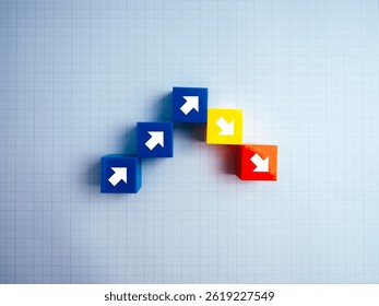 Crisis chart and down graph. Economic downturn with Increase and decrease arrow on multicolored cube blocks steps on graph paper background. Business volatility trend process, financial concept.