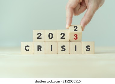 Crisis management concept in new year 2023 . Unexpected situation effects to business and life. Hand flips wooden cubes 2022 to 2023 with text "CRISIS" on beautiful grey background and copy space. 