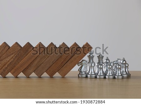 Crisis management, risk management, crisis solving or problem solving concept. Chess stopping wooden dominoes from collapsing.