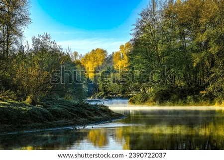 A crisp fall morning on the Sammamish River, with colorful trees and the blue sky reflected in the still water.