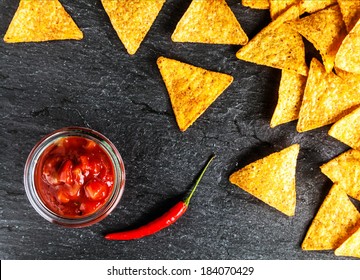 Crisp Golden Corn Totillas With Hot Salsa Sauce And A Red Hot Chili Pepper For A Spicy Snack, Overhead View On A Slate Surface