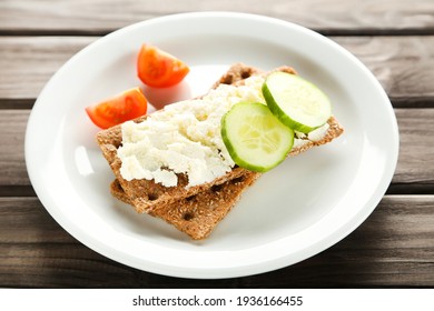 Crispbread with cream cheese and vegetables on wooden table