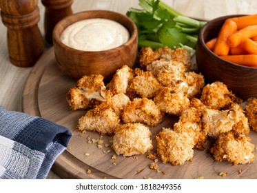 Crispy air fried cauliflower florets and ranch dip with carrots and celery on a wooden tray