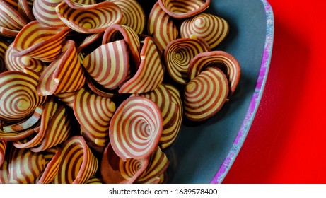 Crispy Biscuits Named Elephant Ears/ Cow Ears Or Pig Ears, Are Isolated On A Purple Plate With A Red Background