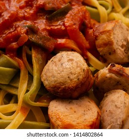 Crispy Bite-sized Pieces Of German Bratwurst With Green And Yellow Ribbon Noodles With Mashed Vegetables In Tomato Sauce