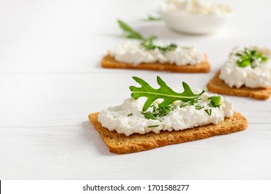 Crispy Bread Crackers With Cottage Cheese And Green Herb On White Background. Copy Space.