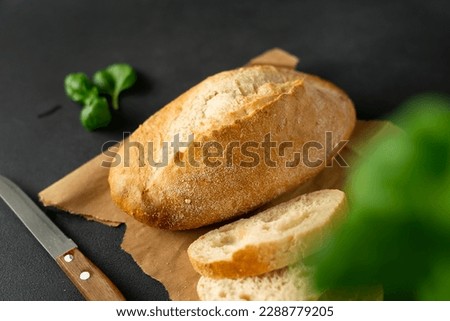 Crispy Bread and kitchen knife, basil on a black background. Sliced fresh white bread. Food background