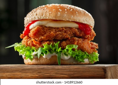 Crispy, Breaded Chicken Burger With Mozzarella Cheese Standing On Wooden Cutting Board