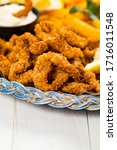 Crispy Breaded Clam Strips Snack Size. Deep Fried Breaded Clams Fingers and French Fried Potatoes with Tartar Dipping Sauce on a white wooden board. Selective focus.