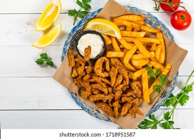 Crispy Breaded Clam Strips Snack Size. Deep Fried Breaded Clams Fingers and French Fried Potatoes with Tartar Dipping Sauce on a wooden board. Selective focus. - Powered by Shutterstock