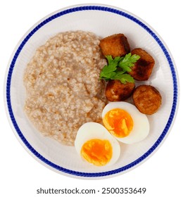 Crispy browned meatballs, rich oatmeal, and perfectly halved soft-boiled eggs, arranged on white plate. Isolated over white background - Powered by Shutterstock