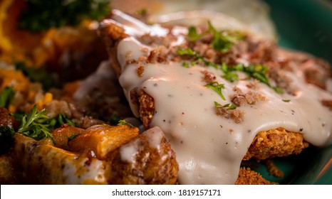 A Crispy Chicken Fried Steak With Cheesy Potatoes, Eggs And Gravy.