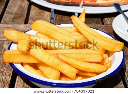 Crispy chunky chips in a metal dish on a wooden table within the citadel, Victoria (Rabat), Gozo, Malta, Europe.