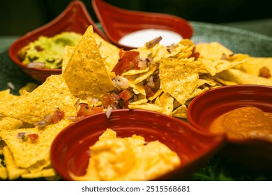 Crispy corn chips served with four flavorful sauces: guacamole, salsa, yogurt sauce, and cheddar. A vibrant and tasty appetizer perfect for sharing and dipping.