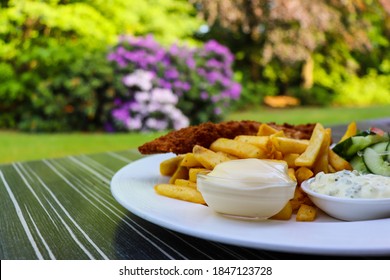 Crispy And Crunchy Fish And Chips With Sauces And Salad. Delicious Dinner Outdoors. Plate Of Tasty Food On The Table Outside. Outdoor Dining. Nutritious And Fulfilling Meal. 