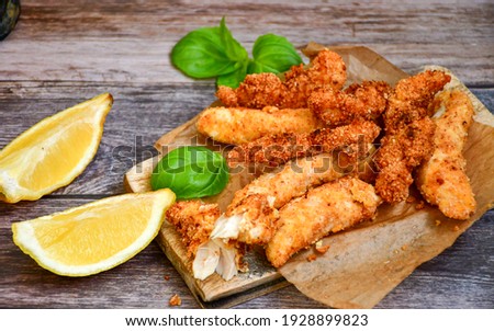 
 Crispy  deep fried home made    chicken strips Breaded  with  almond flour chicken  breast fillets  with chilly peppers and fresh   basil on wooden rustic background. Ketogenic diet food