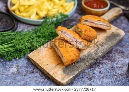  Crispy  deep fried home made     chicken Cordon bleu with cheese   and ham  and french fries on wooden rustic background.  