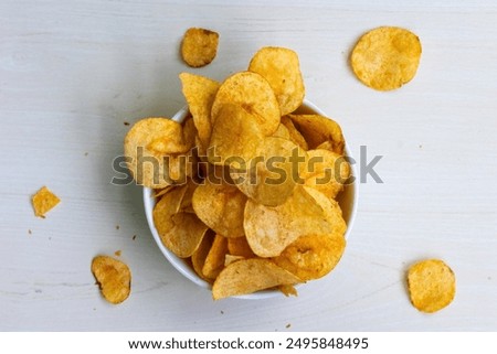 Crispy and delicious potato chips or crisps on wooden background. Top view of tasty lays Spanish tomato tango flavor potato chips.
