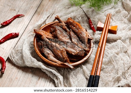 Crispy dried small fish on flower plate with dark purple cloth