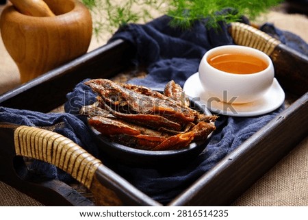 Crispy dried small fish on flower plate with dark purple cloth