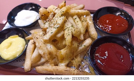 Crispy French Fries Stuffed With Cream Sauce And Mozzarella Cheese And A Sprinkling Of Oregano Powder, Served With Chili Sauce, Tomato Sauce, Cheese Sauce On A Small Plate.