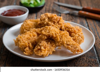 Crispy fried breaded chicken strips on plate and ketchup
