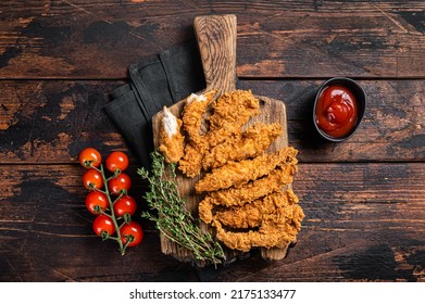 Crispy fried Breaded chicken strips, breast fillet meat with tomato ketchup on a plate. Wooden backgrund. Top view.