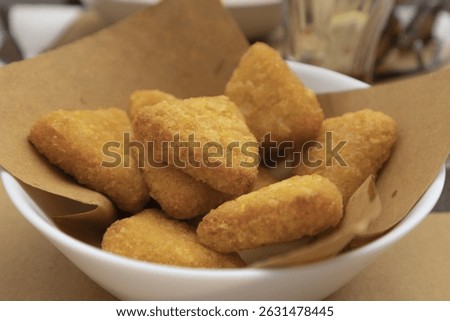 crispy fried breaded triangles, great for an aperitif, in a white bowl with absorbent paper seen in close-up, cheese