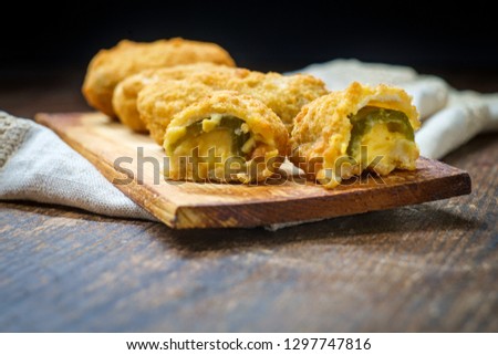 Crispy fried cheddar cheese jalapeno popper bites served on wooden cedar plate with dark moody lighting