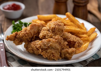 Crispy Fried Chicken Tenders And French Fries Garnished With Parsley On A Plate