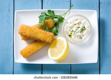 Crispy Fried Fish Fingers With Lemon And Sauce On Blue Wooden Background. Top View