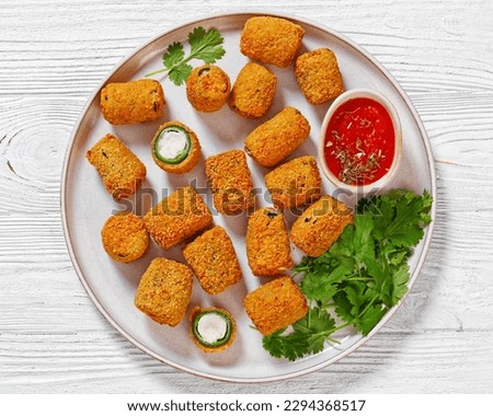 crispy fried jalapeno poppers with melted cream cheese filling on white platter on white wood table, horizontal view from above, flat lay, close-up